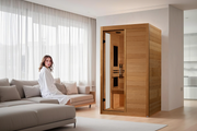 Woman in a robe sitting on a couch next to a wooden sauna in a modern living room.