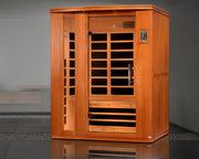 Wooden infrared sauna in a room with a gray floor and wall.