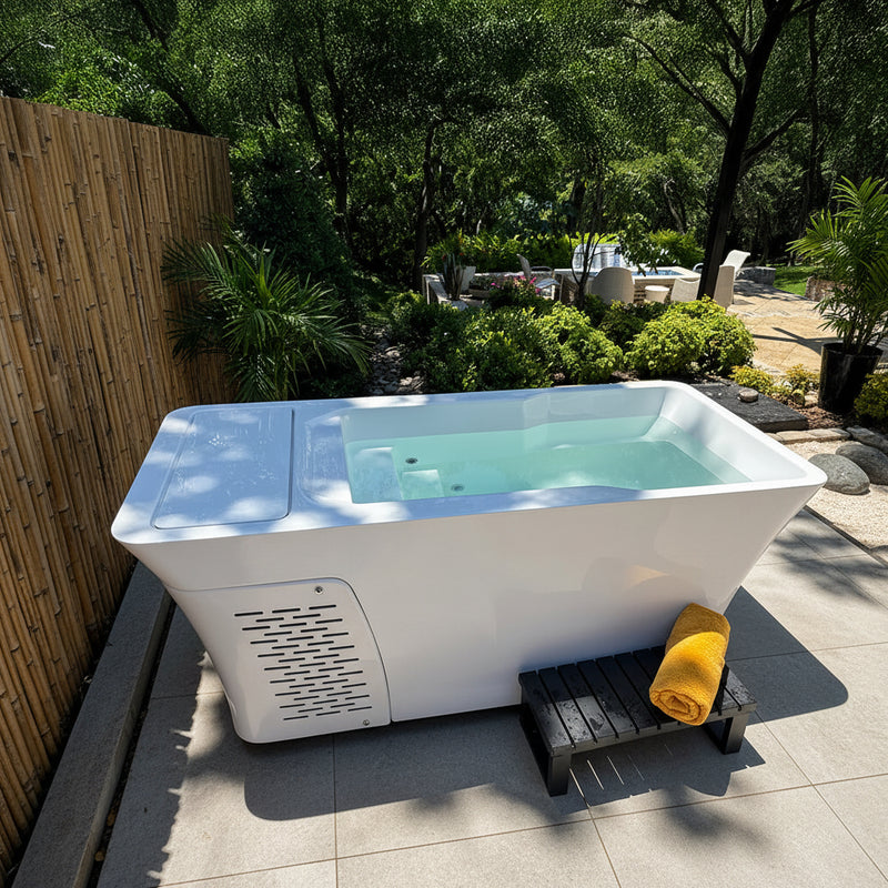 Outdoor cold plunge tub with a yellow towel on a wooden platform, surrounded by greenery.