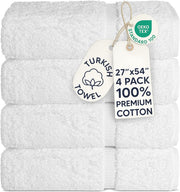 A stack of four folded white Turkish towels with attached paper tags, including an OEKO-TEX Standard 100 badge and a size/quality tag reading 27"x54" 4 PACK 100% PREMIUM COTTON.